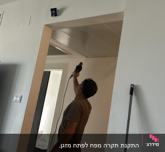 אדם מתקין מכשיר על קיר בחדר